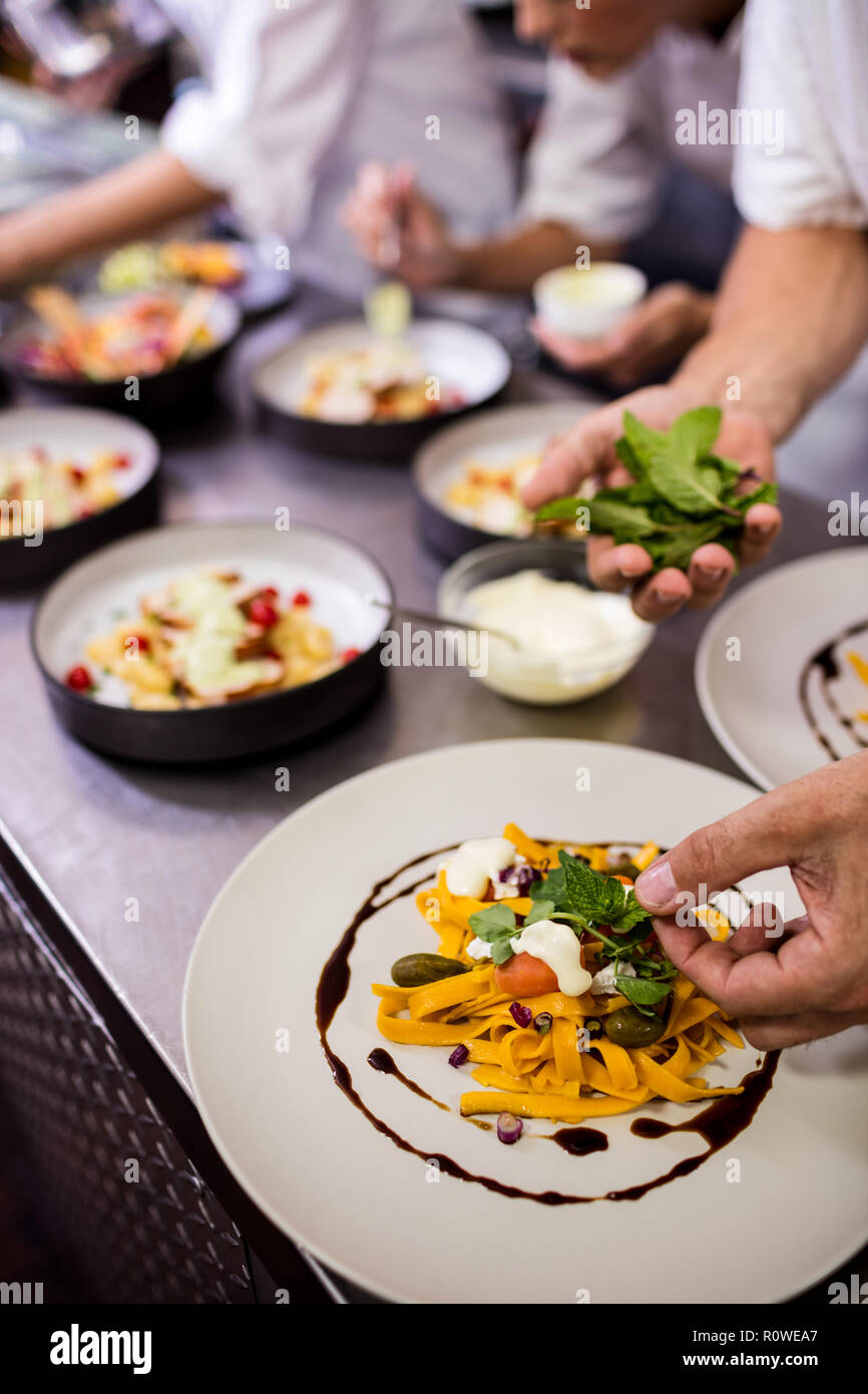 Chef garnishing food on plates Stock Photo