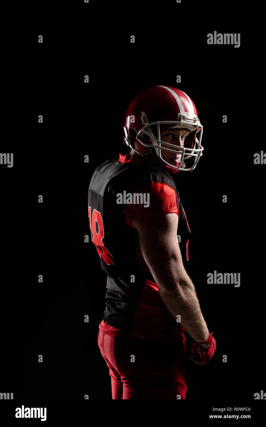 American football player in helmet standing against black background Stock Photo