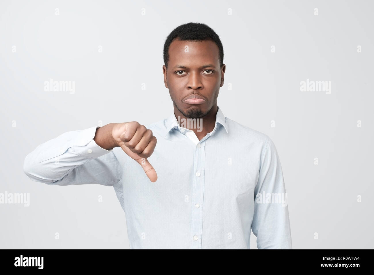 Unhappy, angry, mad and grumpy man giving thumbs down gesture Stock