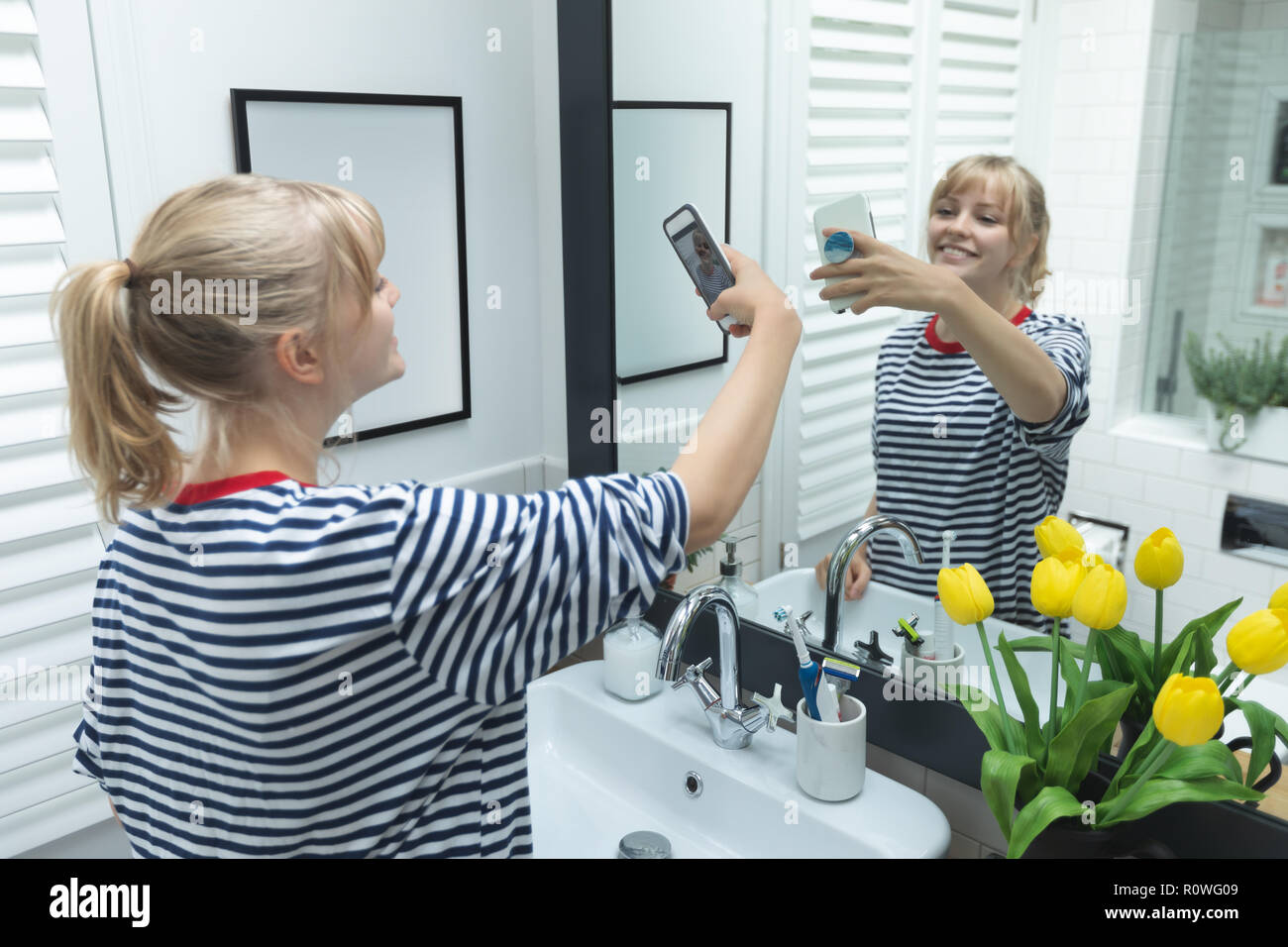 Woman taking selfie on mobile phone in bathroom Stock Photo