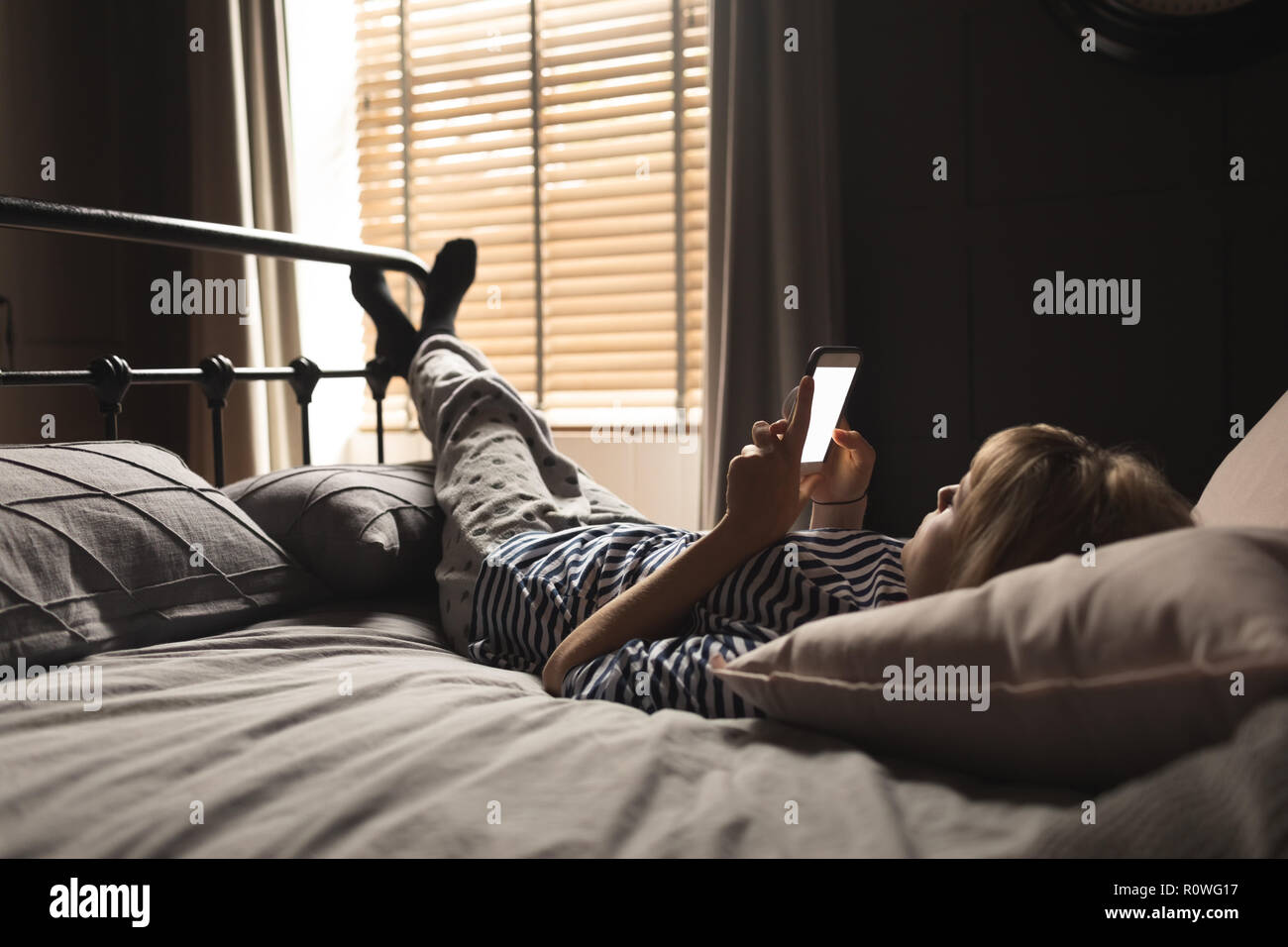 Woman using mobile phone on bed in bedroom Stock Photo Alamy