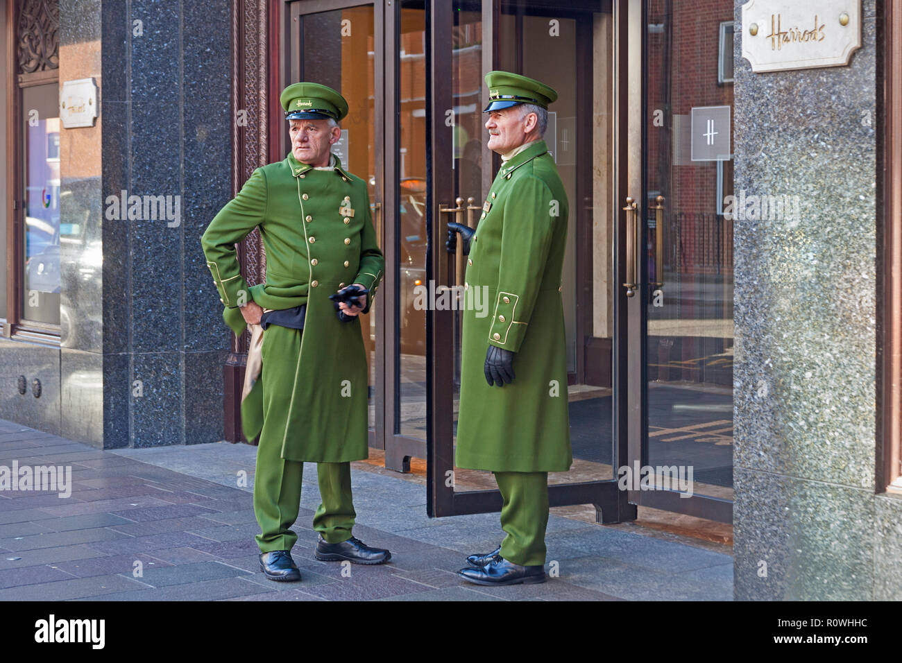 London, Knightsbridge.  Uniformed doormen resting from their duties at the entrance to Harrods department store. Stock Photo