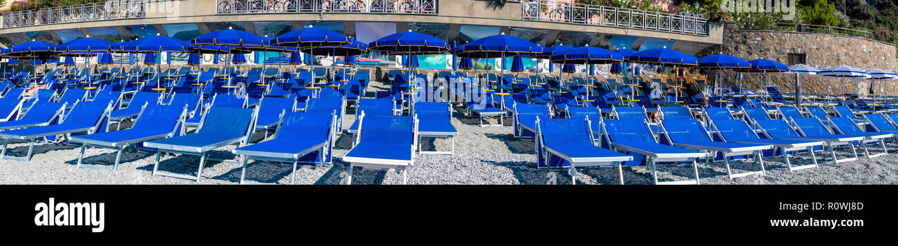 Panoramic view of blue chairs and parasol on the beach of Monterosso Al Mare village Italy Stock Photo