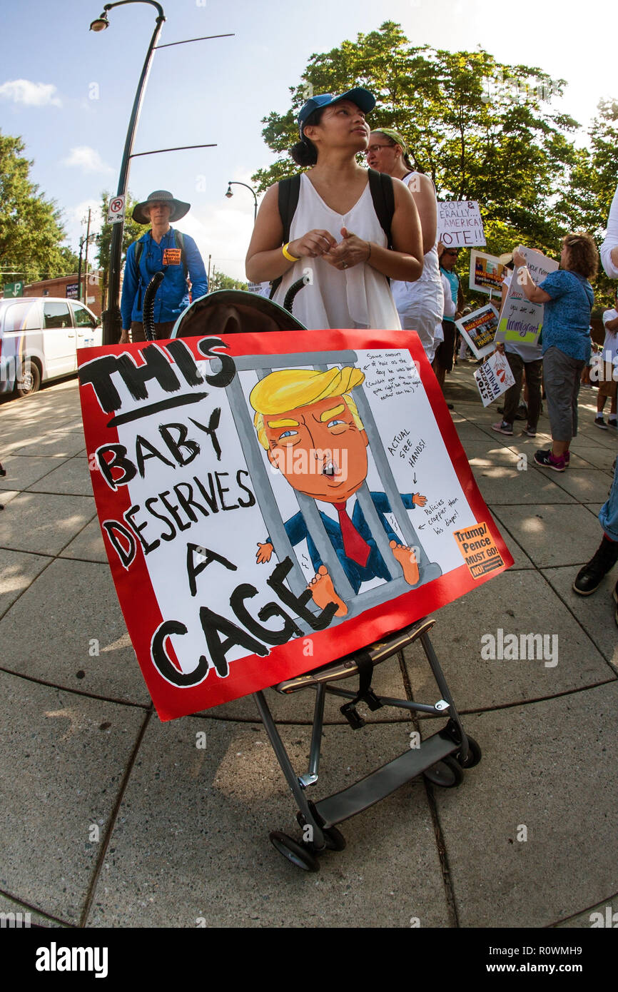A woman transports an anti-Trump sign in a baby stroller, as she and ...
