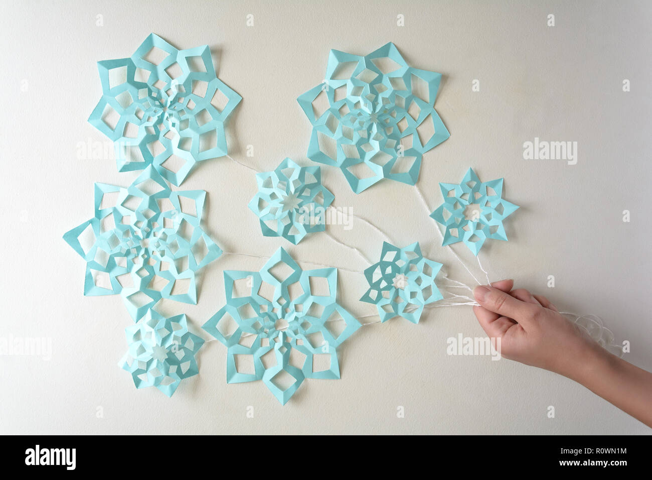 Hand Holding Blue Paper Snowflakes Balloons With Threads Laying
