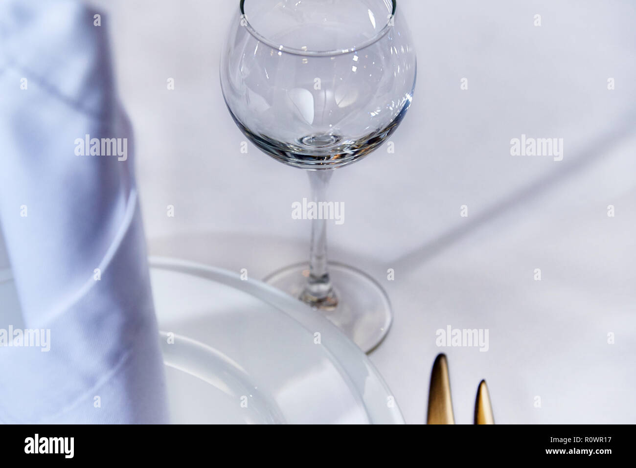 An empty glass near the plate with a napkin on a served table. Stock Photo