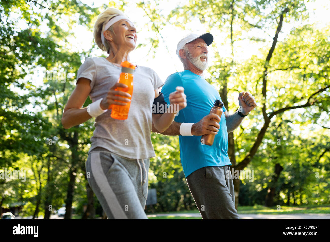 Fitness, sport, people, exercising and lifestyle concept - senior couple running Stock Photo