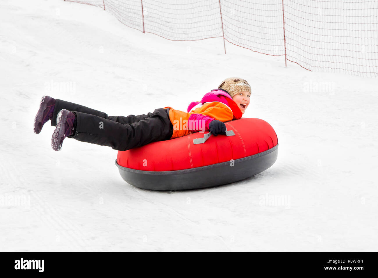 Child girl on snow tubes downhill at winter day. Stock Photo