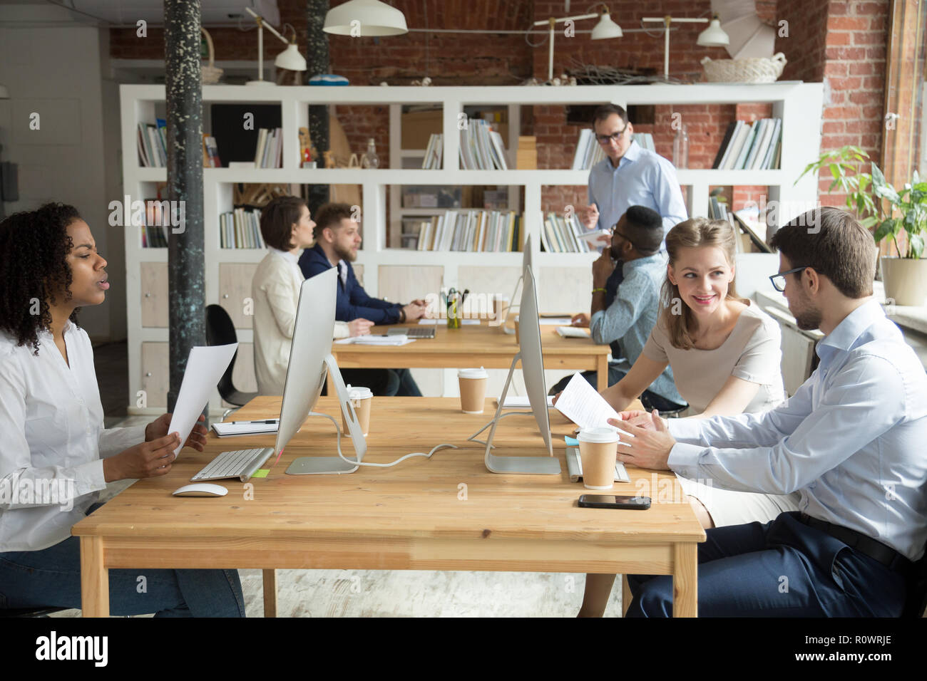 Multiracial employees working at computers together discussing p Stock Photo