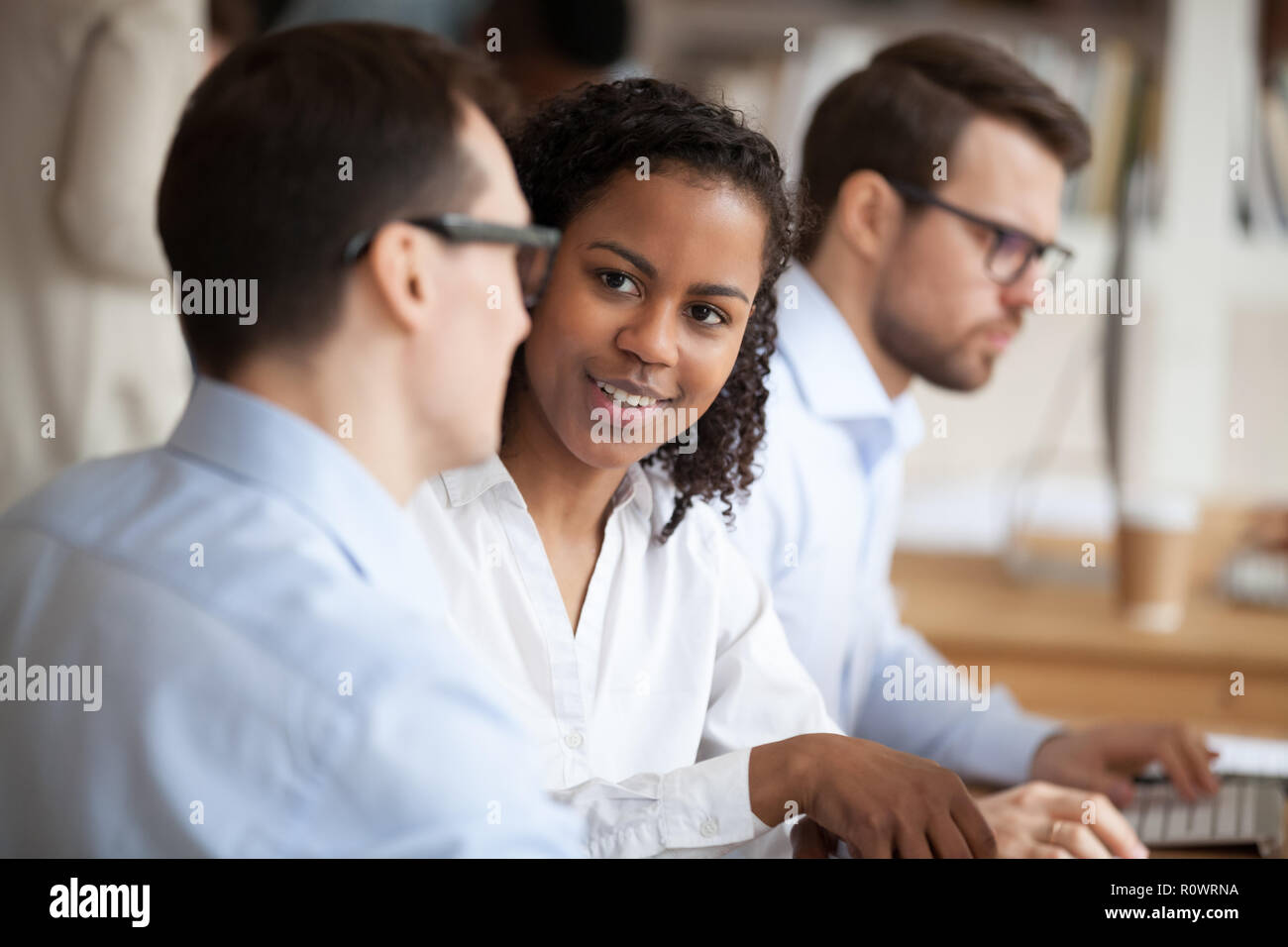 Multiracial employees talk working together in shared office Stock Photo