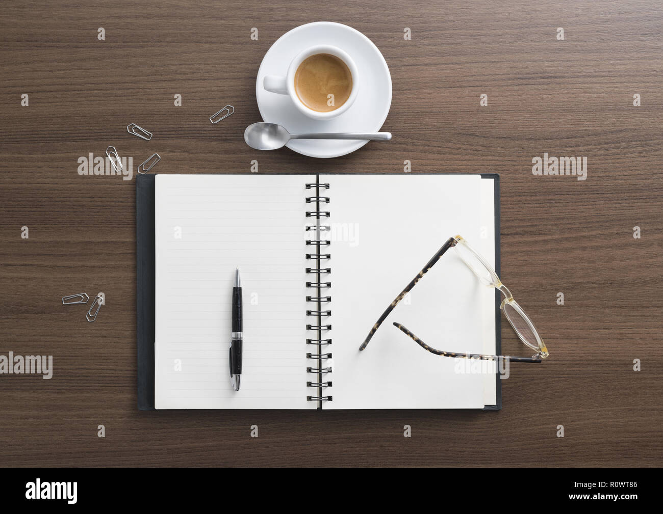 Notizbuch, Kugelschreiber, Brille und Kaffeetasse auf Schreibtisch Stock Photo
