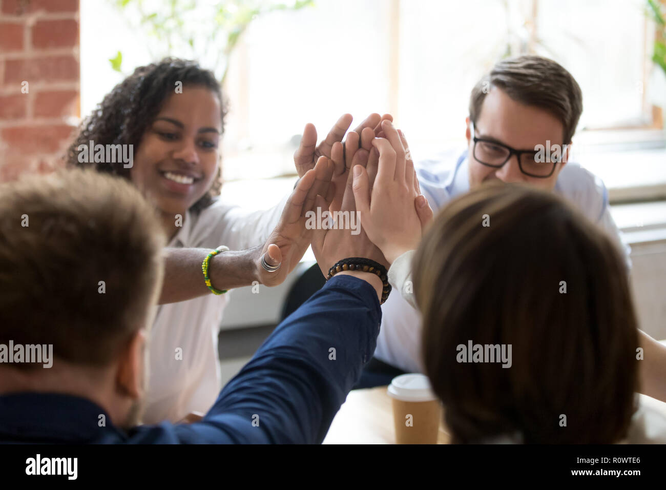 Diverse employees give high five during company office briefing Stock Photo
