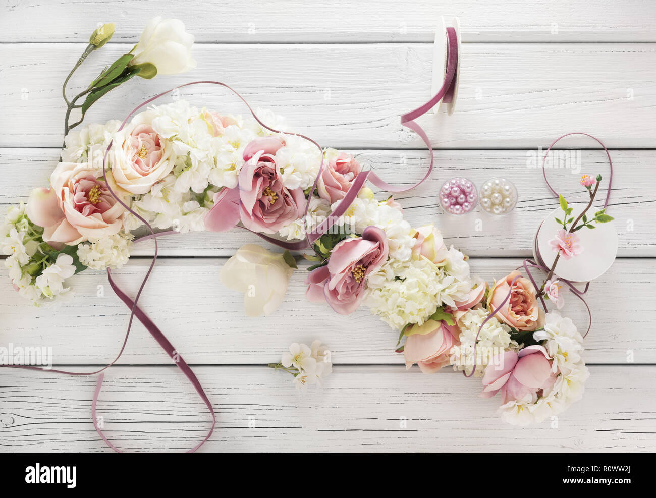 Blumengirlande auf weissem Holztisch Stock Photo