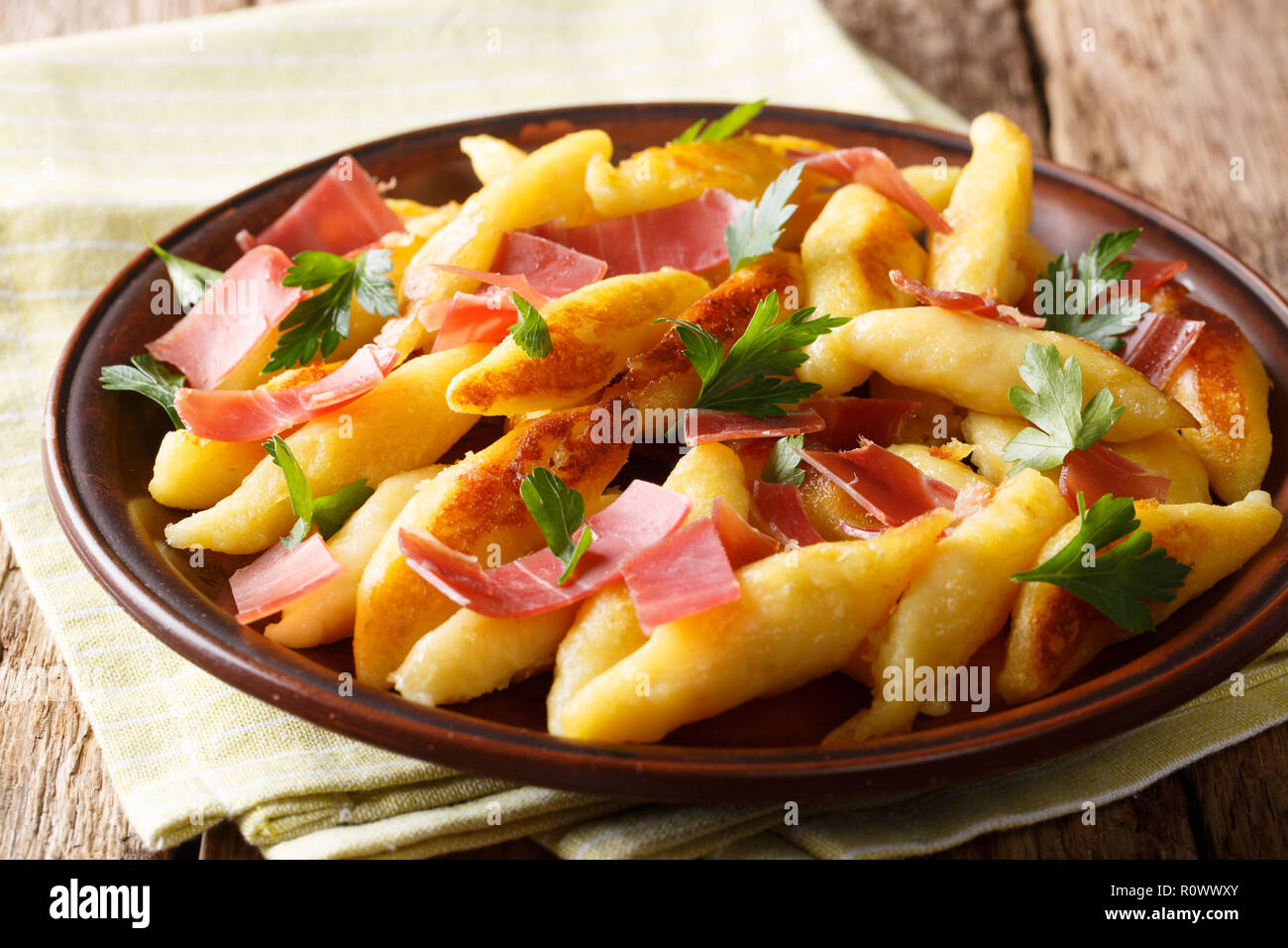 Recipe for German potato noodles called Schupfnudeln, served with bacon and parsley closeup on