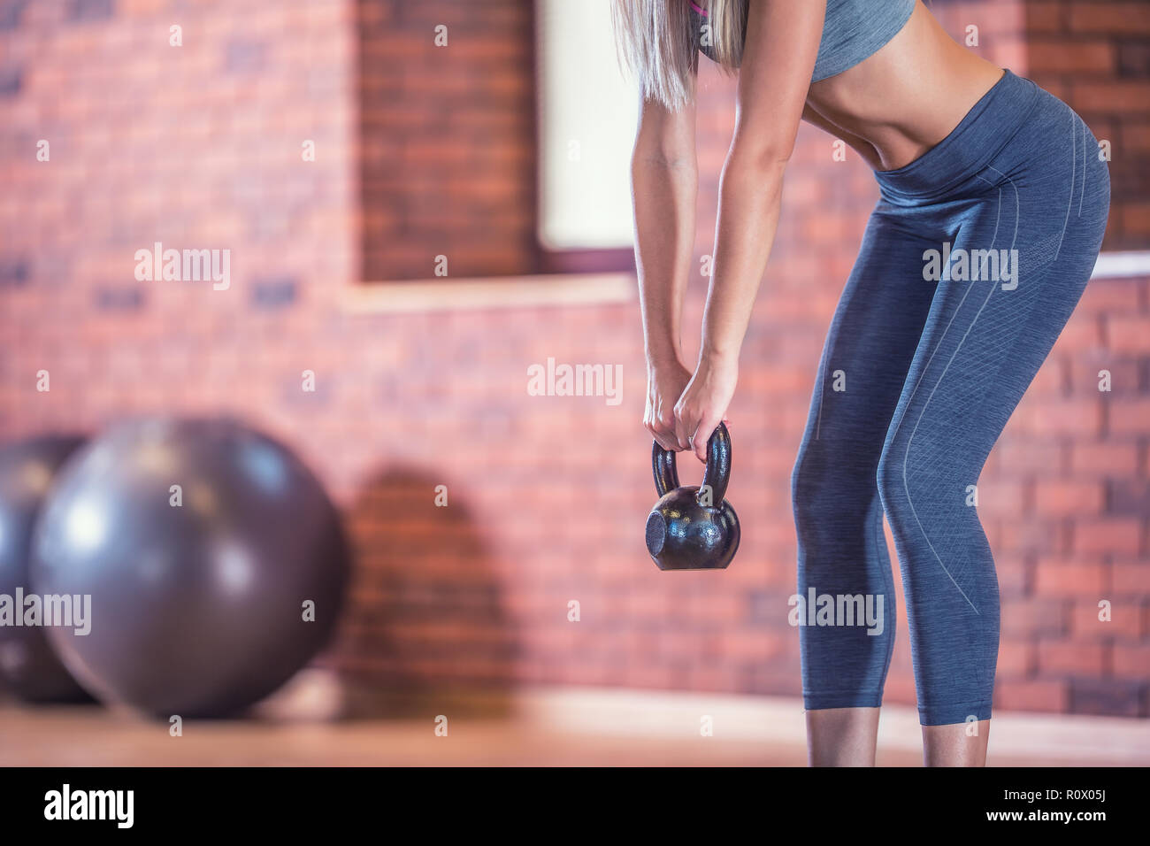Attractive woman with slim body in gym holding a kettlebell. Stock Photo