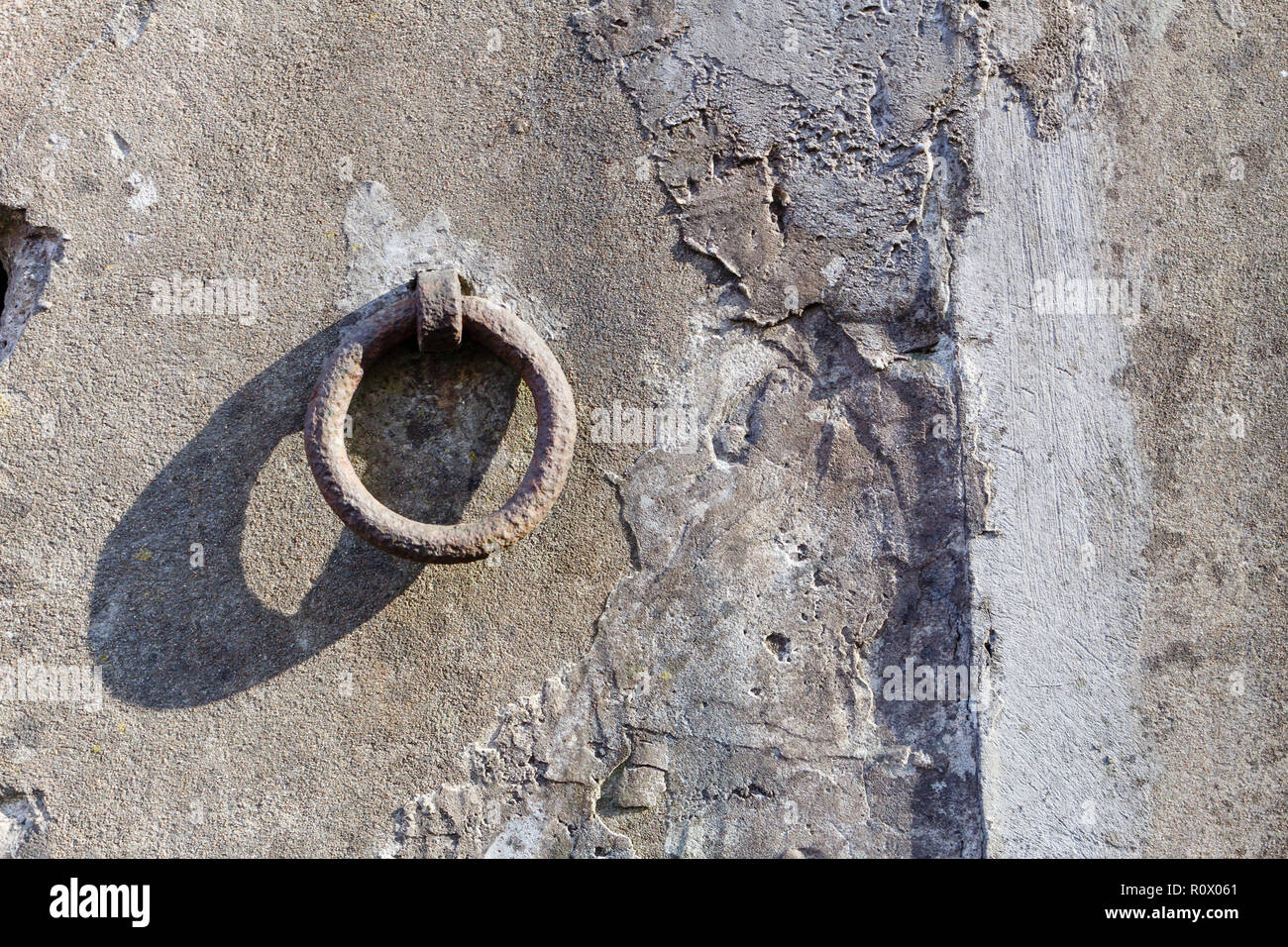 Old iron hoop hanging from stone wall Stock Photo