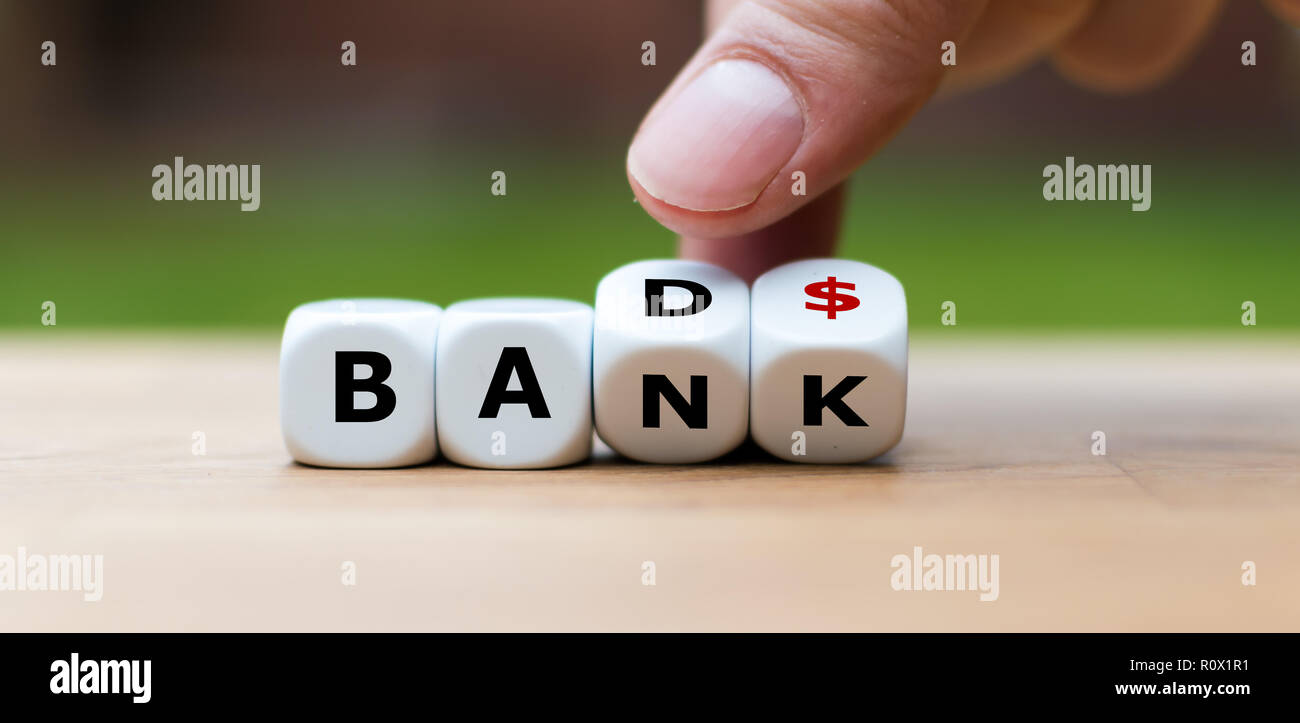 Hand is turning a dice and changes the word 'Bad' to 'Bank' Stock Photo