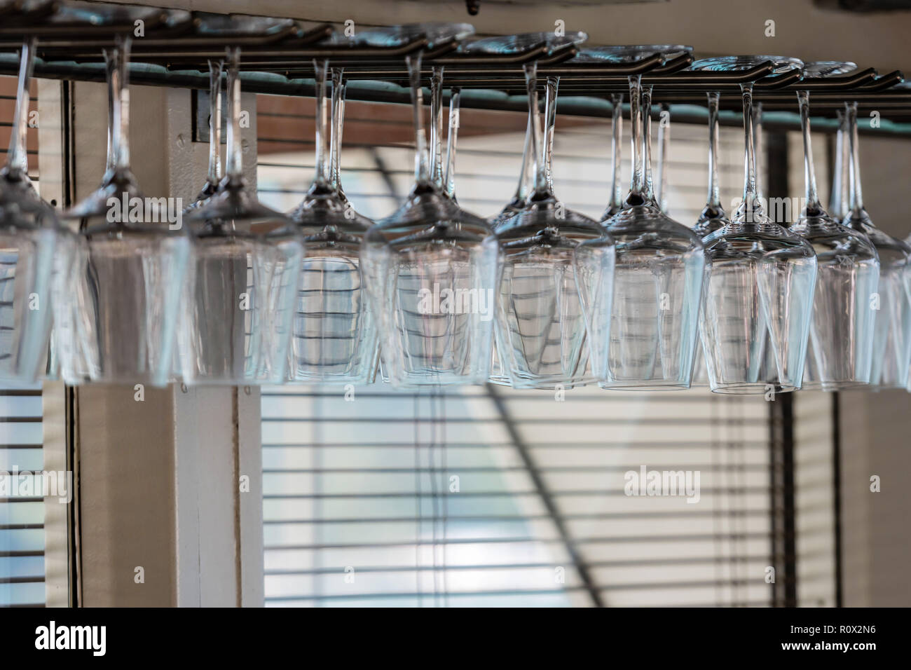 A row of wine glasses hang upside down in the bar. Stock Photo