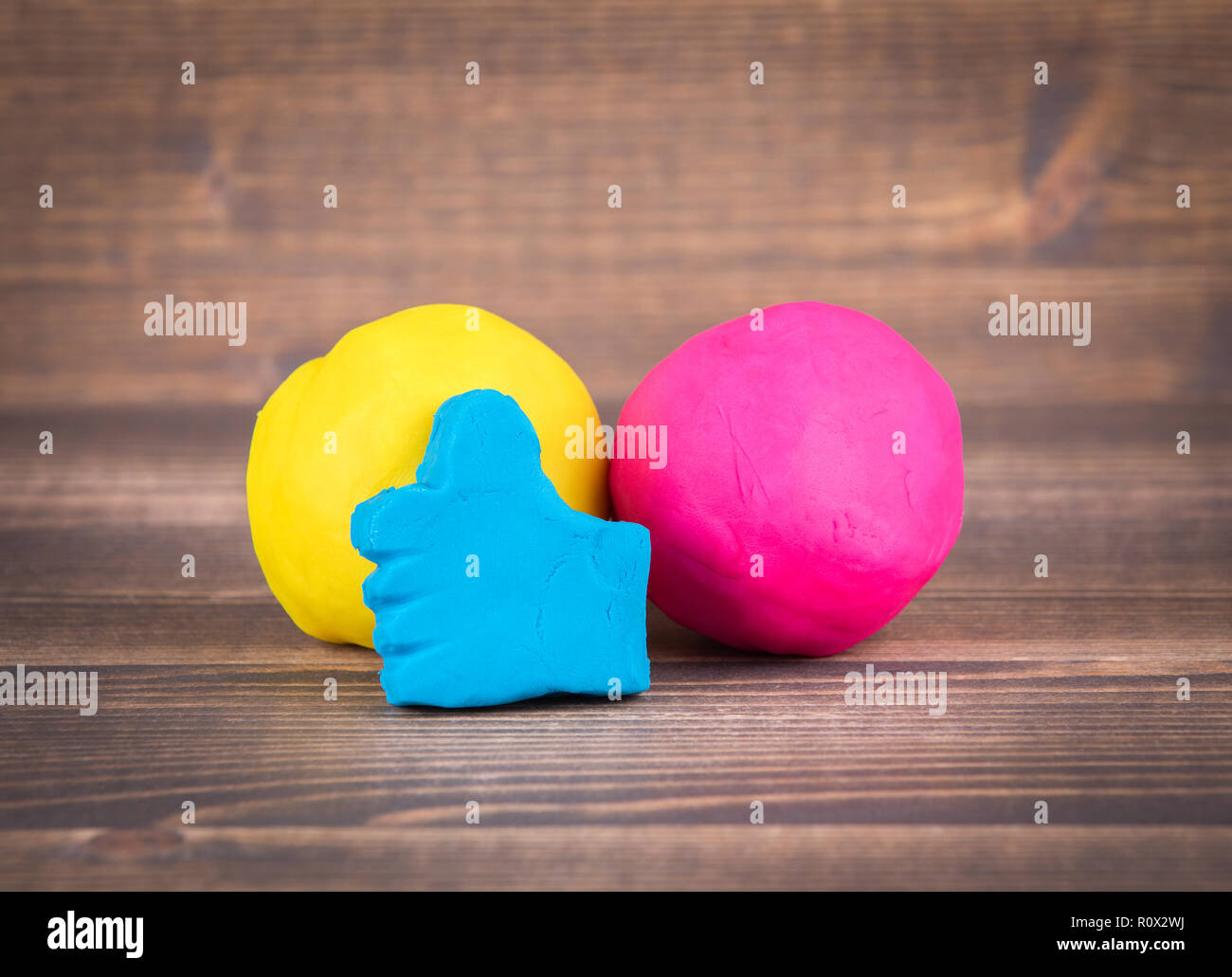 like hand icon from plasticine and multiple colorful balls on wooden ...