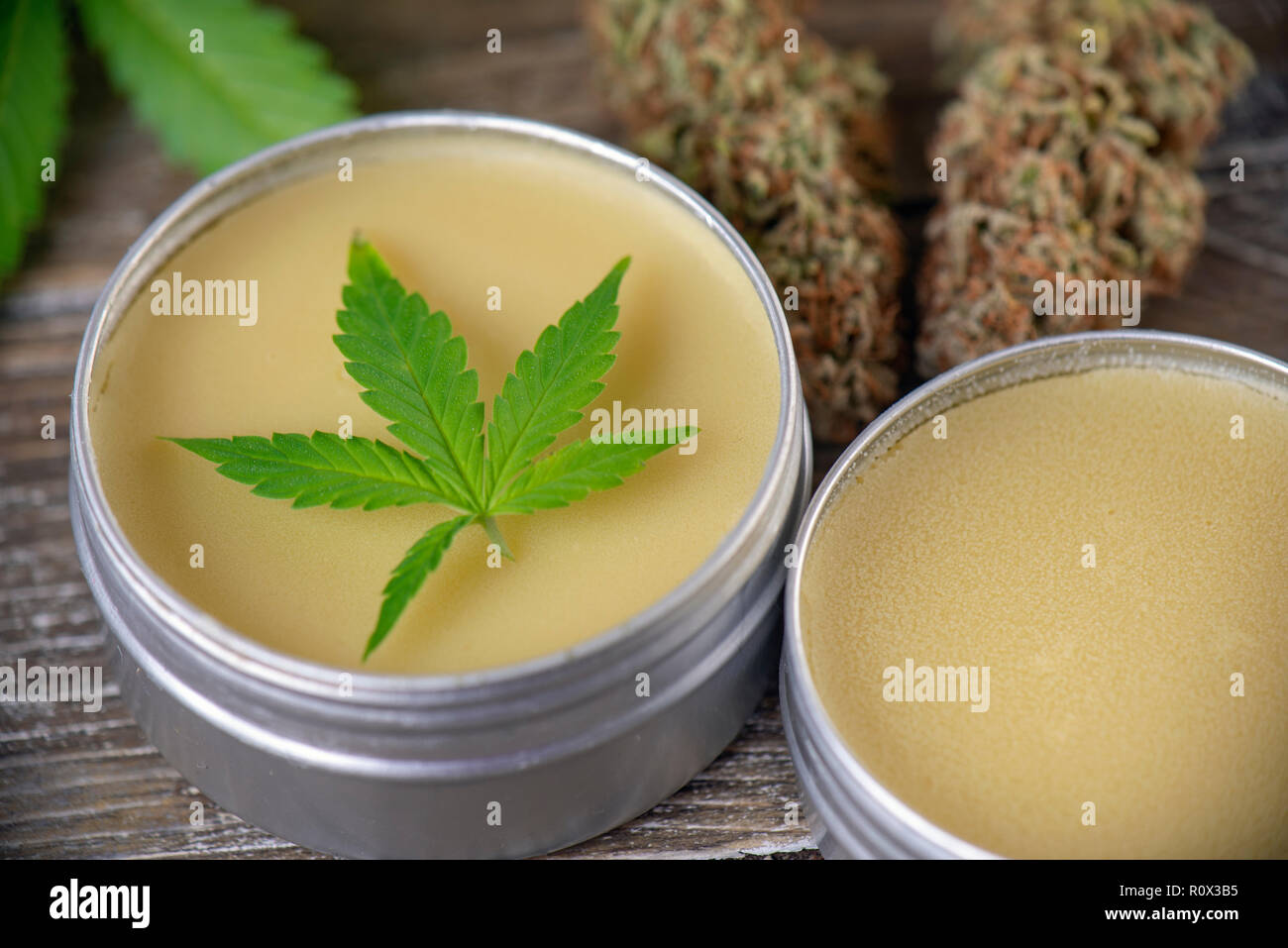 Cannabis hemp cream with marijuana leaf and nug over wood background