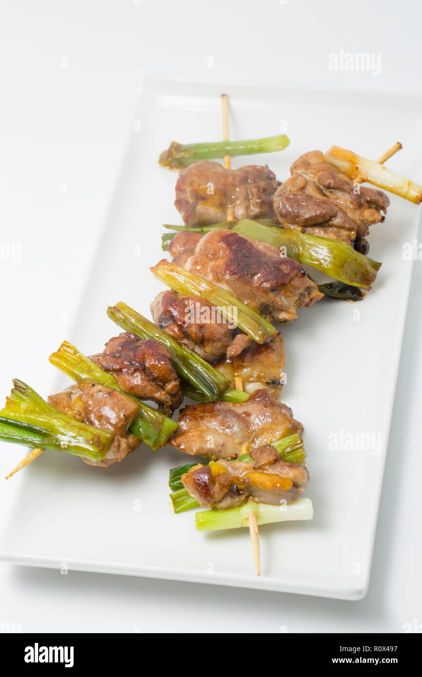 Home-cooked pieces of pheasant thigh meat from a pheasant shot on a driven gameshoot. They have been skewered on bamboo skewers with spring onions and Stock Photo