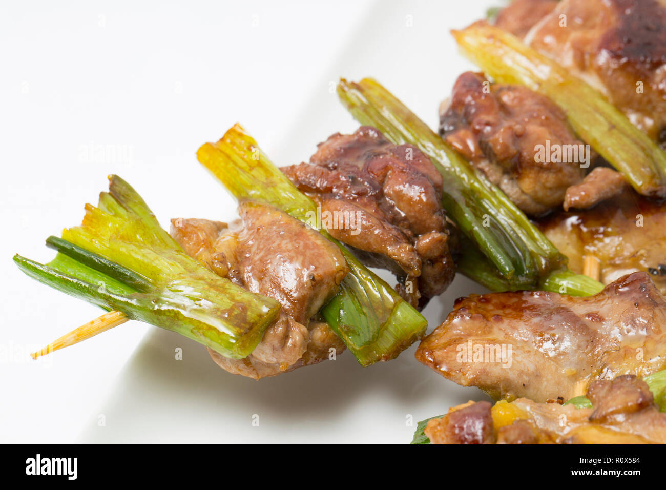 Home-cooked pieces of pheasant thigh meat from a pheasant shot on a driven gameshoot. They have been skewered on bamboo skewers with spring onions and Stock Photo