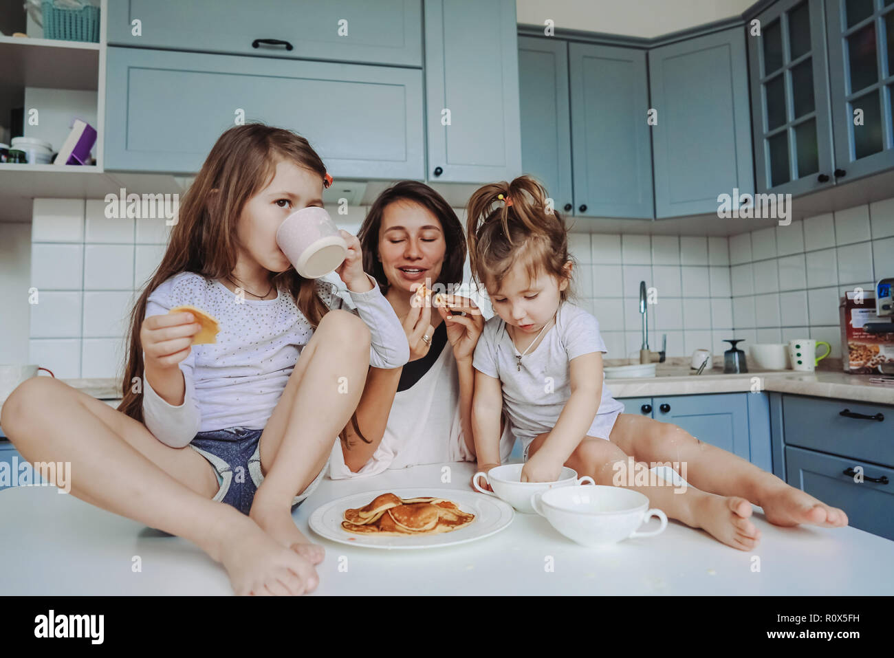 Мама пьет дочку. Фотосессия на кухне с двумя дочками. Фотосессия на кухне мама и две Дочки. Женщина и две Дочки сидят в кафе. Мама с ребенком едят блины.