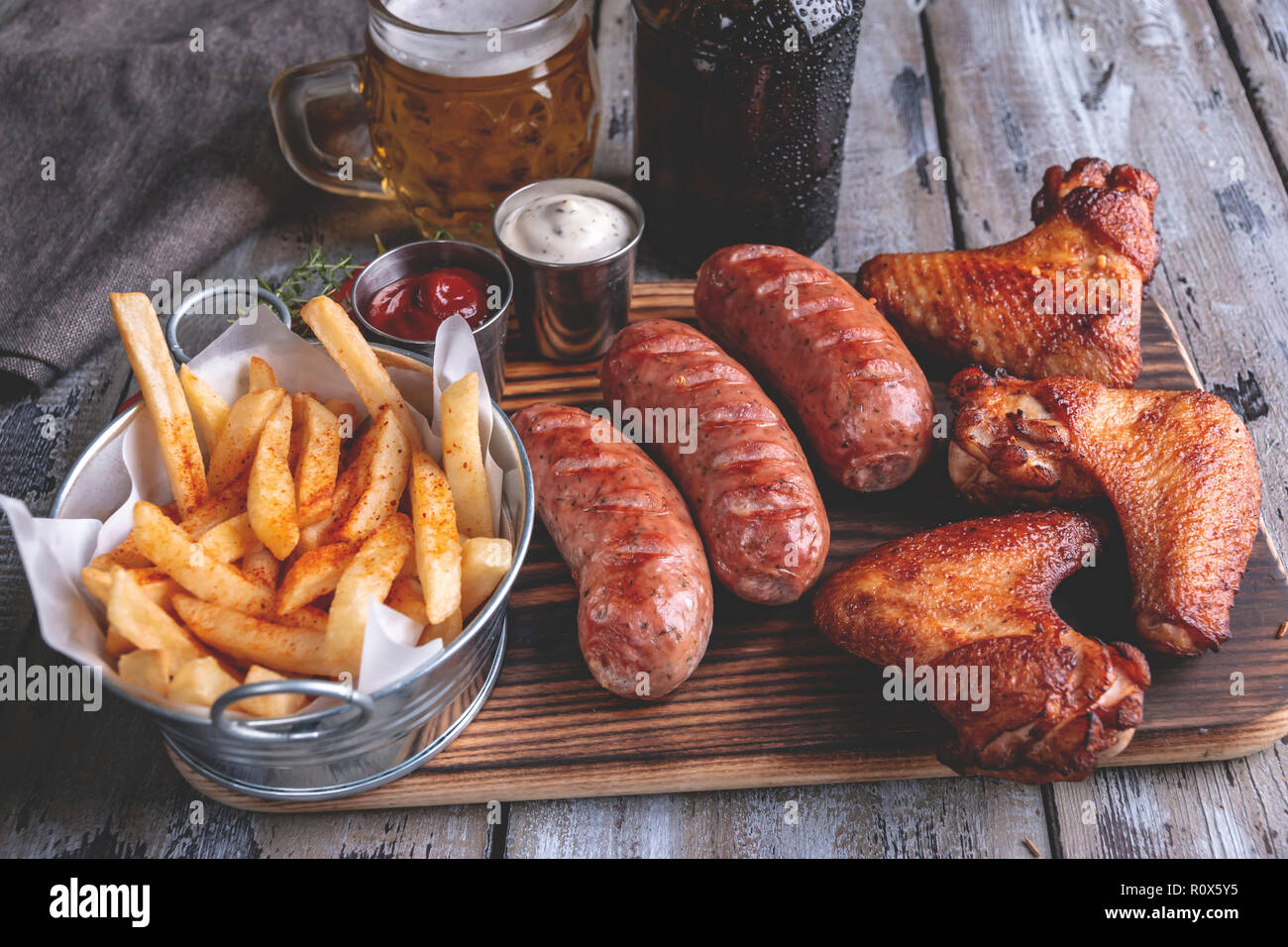 Fried chicken wings,grilled sausages, french fries, white and red sauce. food to beer Stock Photo