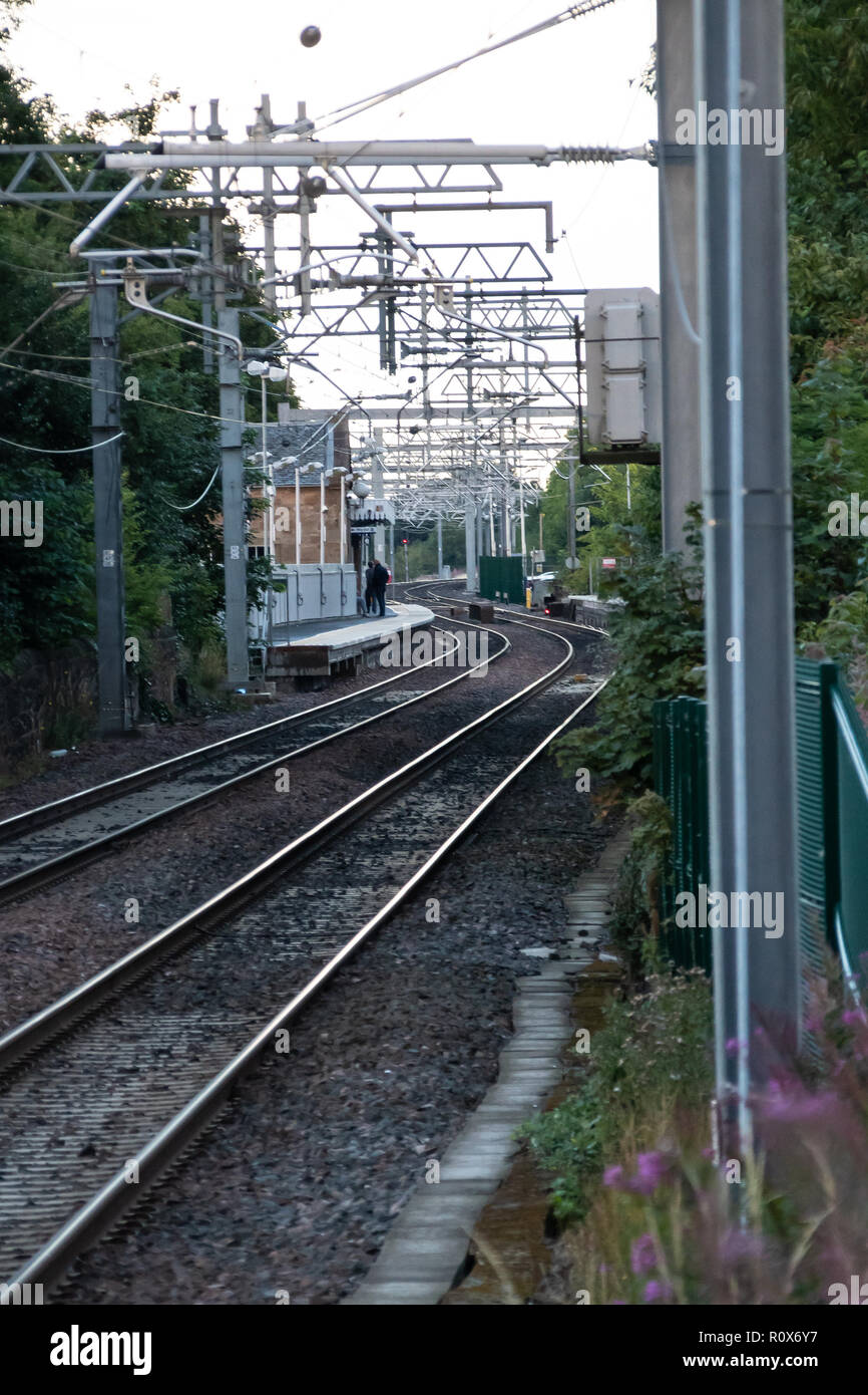 Linlithgow, United Kingdom - August 10 2018:   The tracks leading into Linlithgow railway station with a couple of passengers on the platform Stock Photo