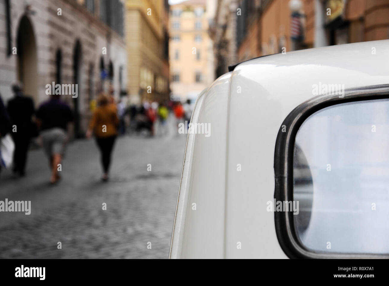 A parked Fiat 500 in the streets of Rome, some people on the background ...