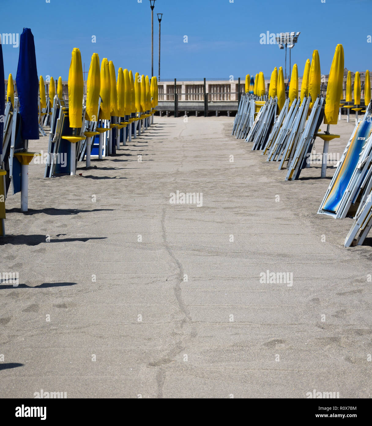 Ostia, Italy - August 12 2017:   Lines of brighlty coloured Parasols and deckchairs await holiday makers on Ostia Beach Stock Photo