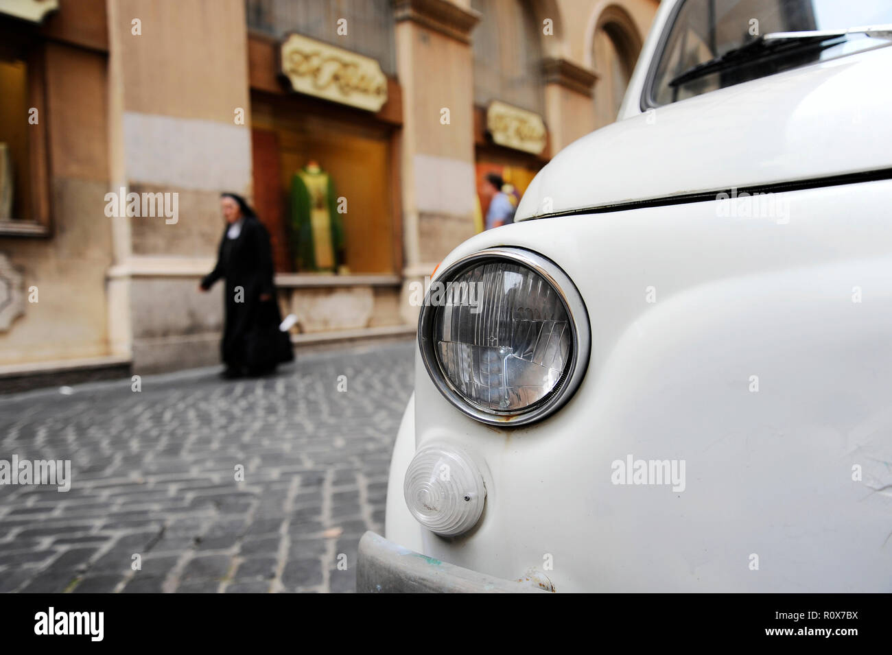 A parked Fiat 500 in the streets of Rome, a nun walking on the ...
