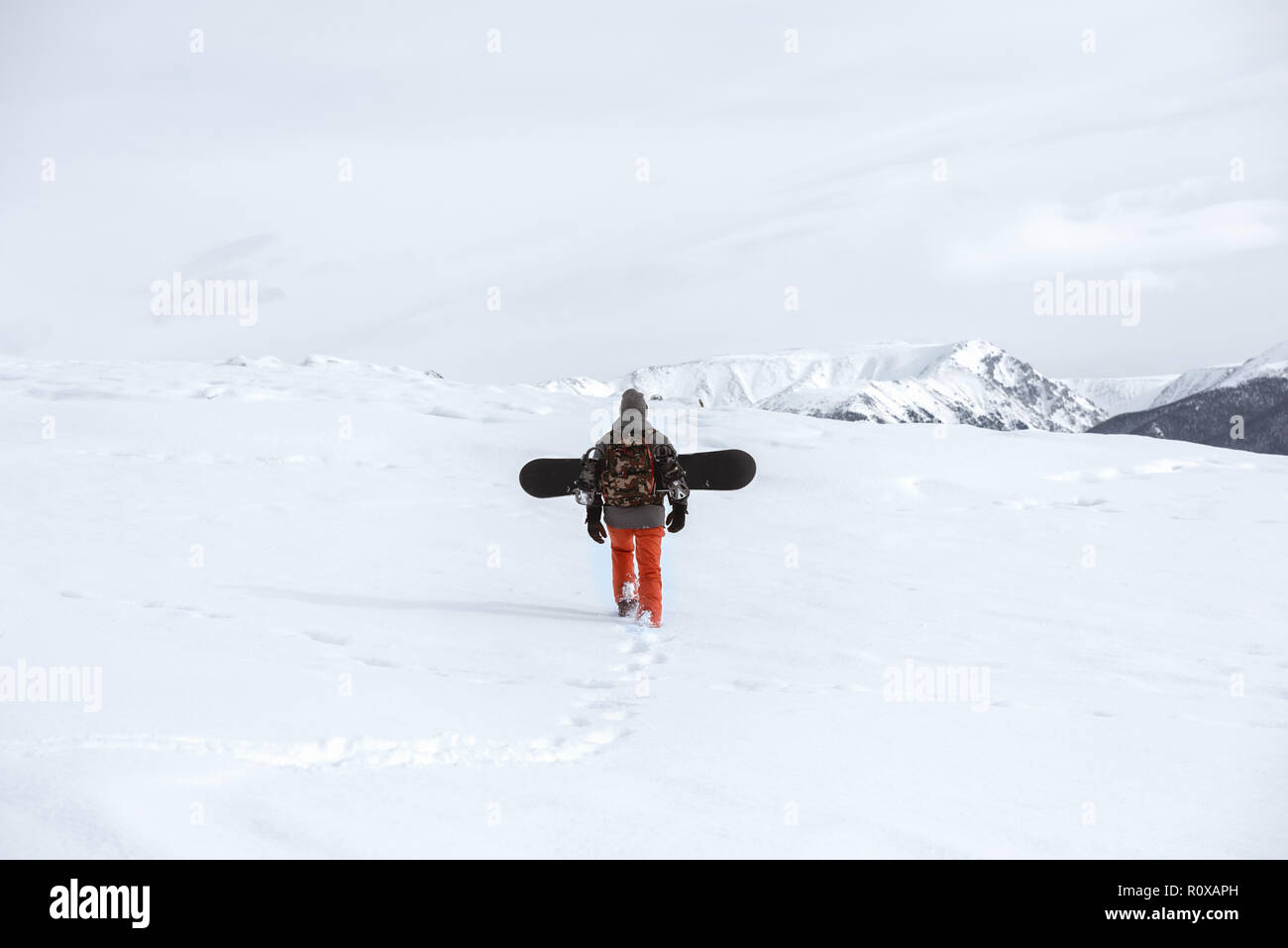 Snowboarder goes uphill at ski tour in mountains Stock Photo