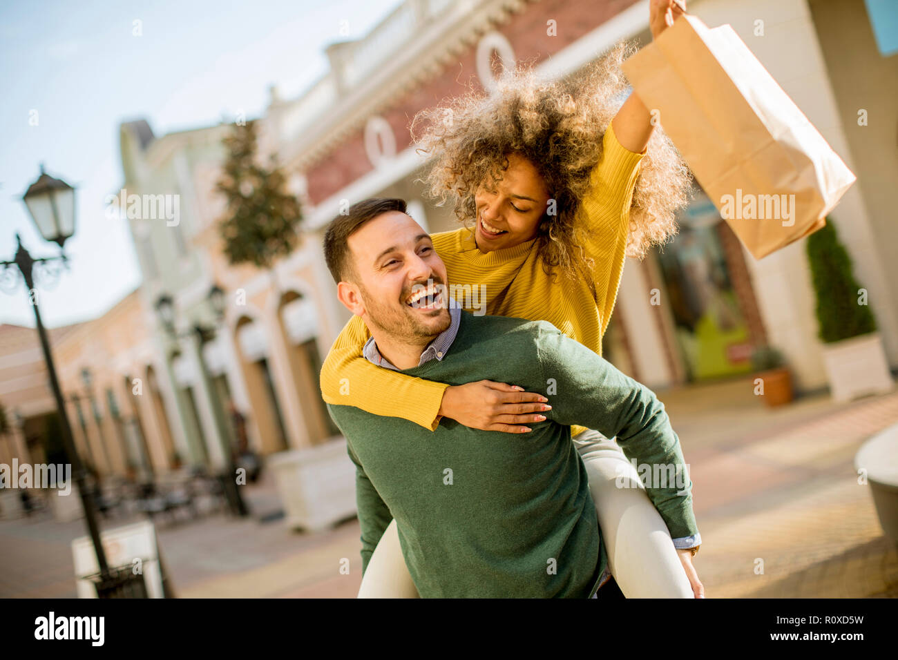 Portrait of  young man holds young woman on his back , have fun and go to shopping Stock Photo