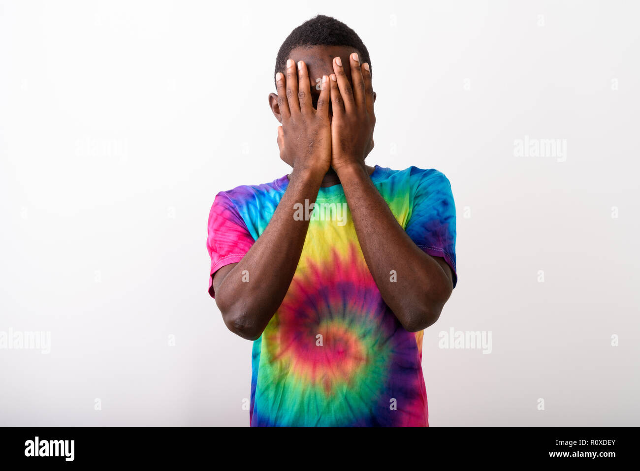Studio shot of young black African man covering his face with bo Stock Photo