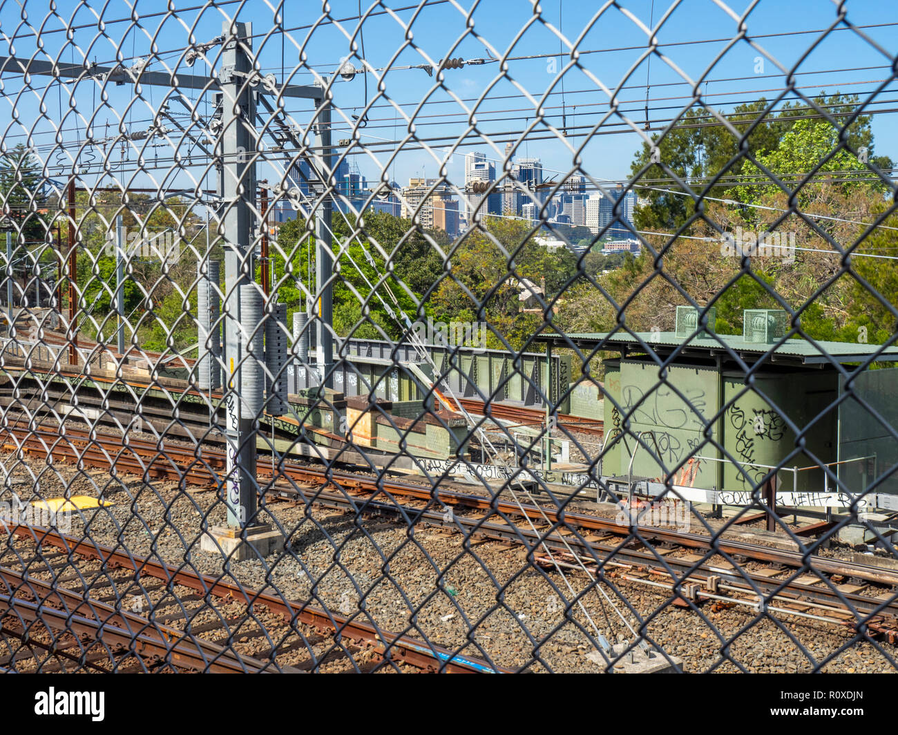 Train railway transport system seen through chain-link cyclone fence Sydney NSW Australia. Stock Photo