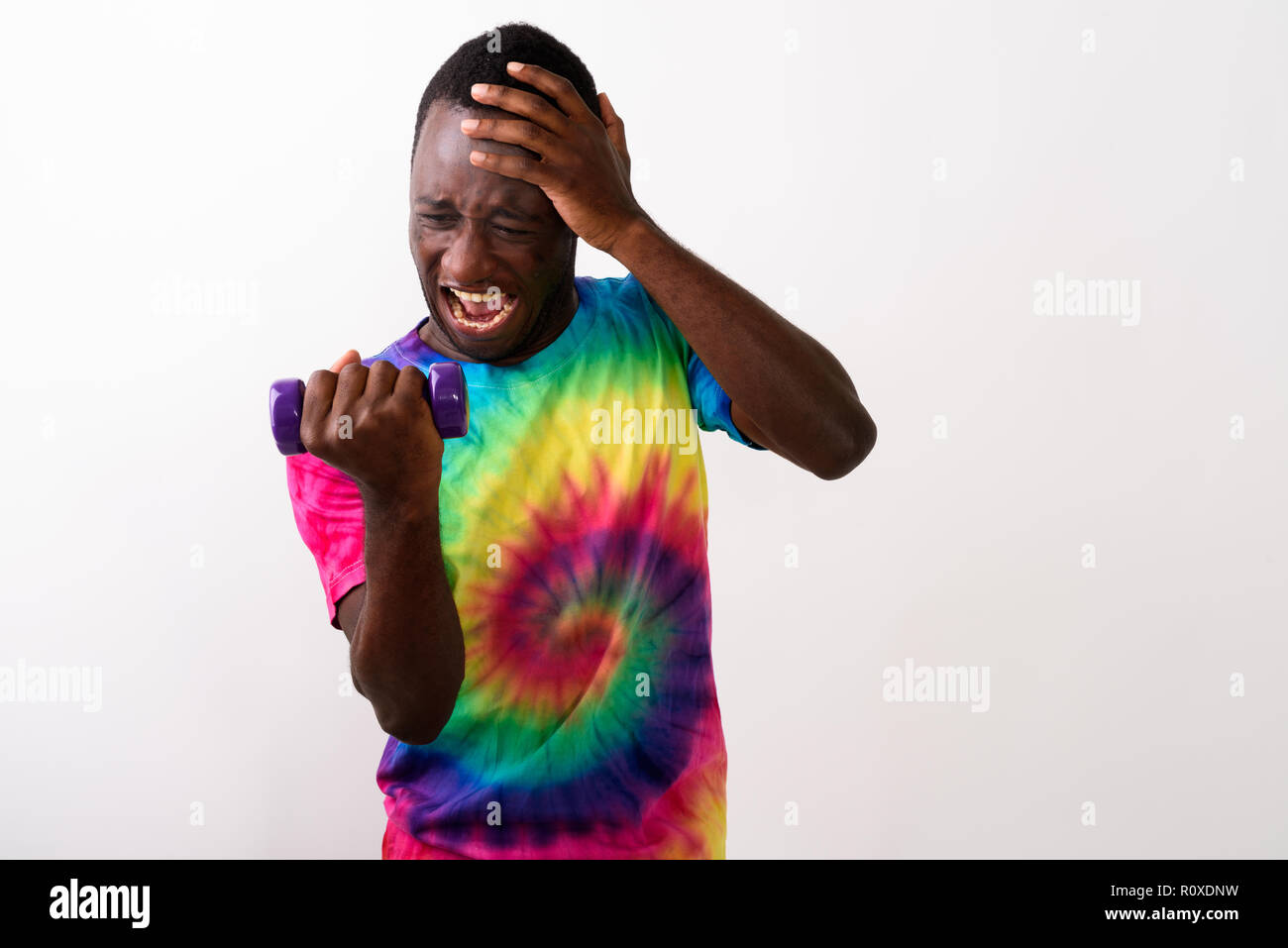 Studio shot of young black African man feeling tired while flexi Stock Photo