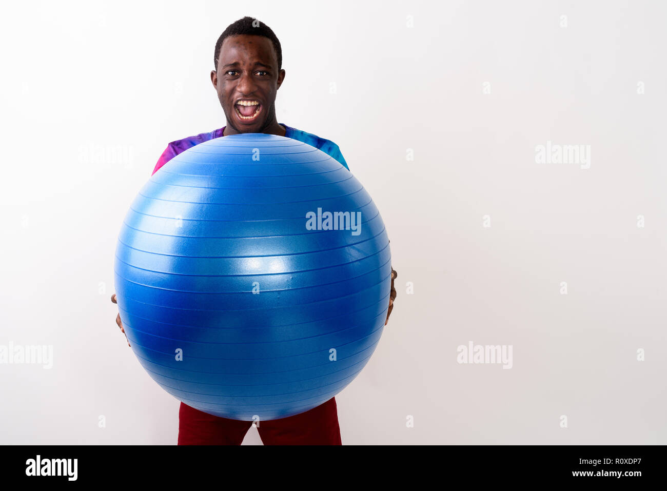 Studio shot of young black African man holding big exercise ball Stock Photo