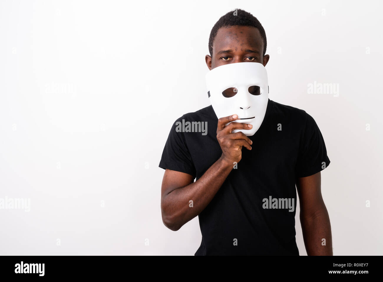 Studio shot of young black African man holding mask in front of  Stock Photo