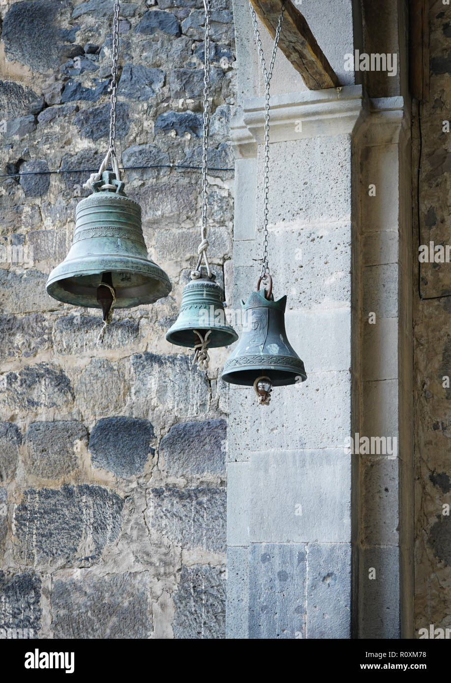 three church bells of small, medium and large size hanging in chains Stock Photo