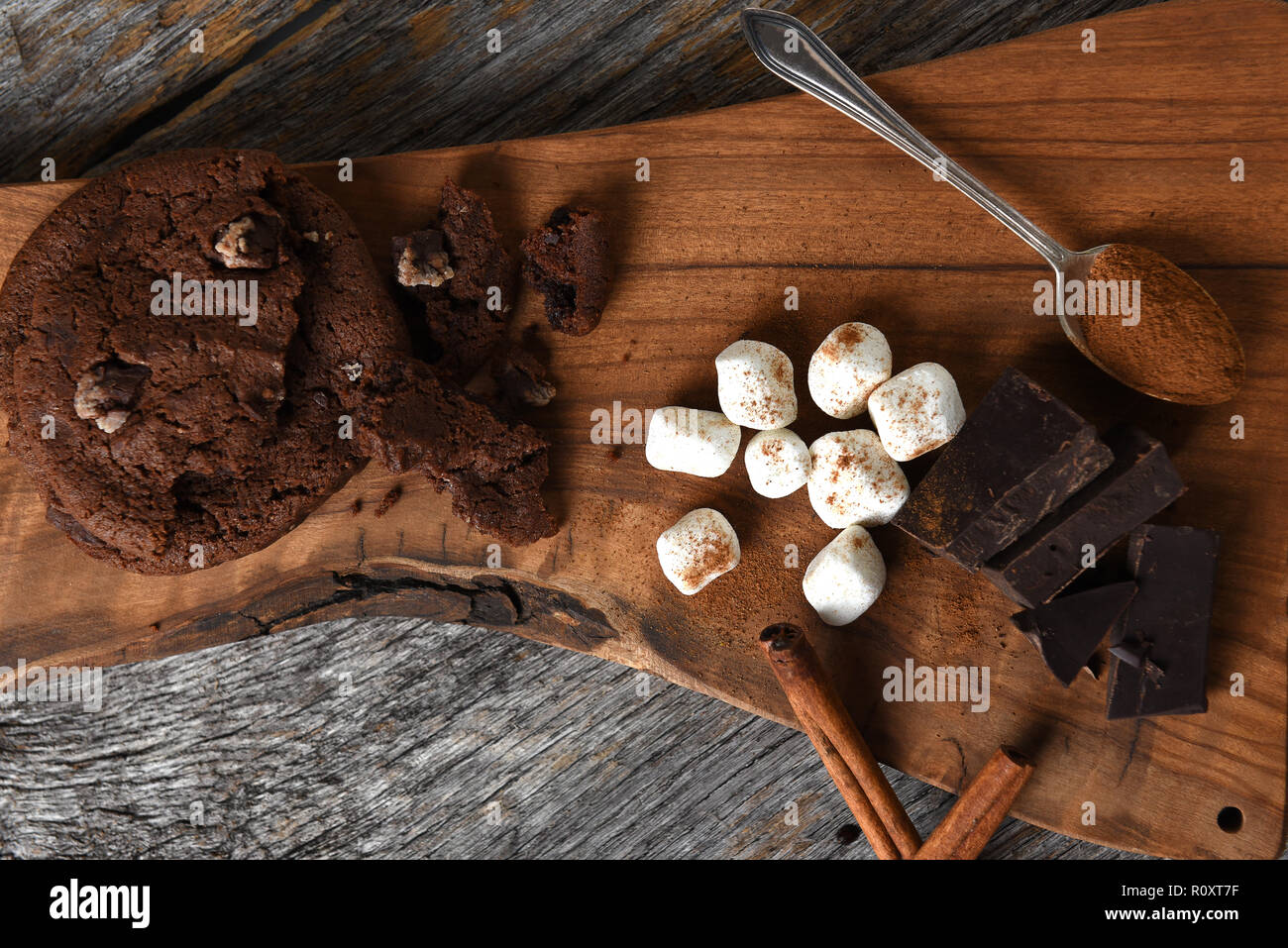 Overhead shot of a cutting board with chocolate chunks cinnamon sticks and cookies. Stock Photo