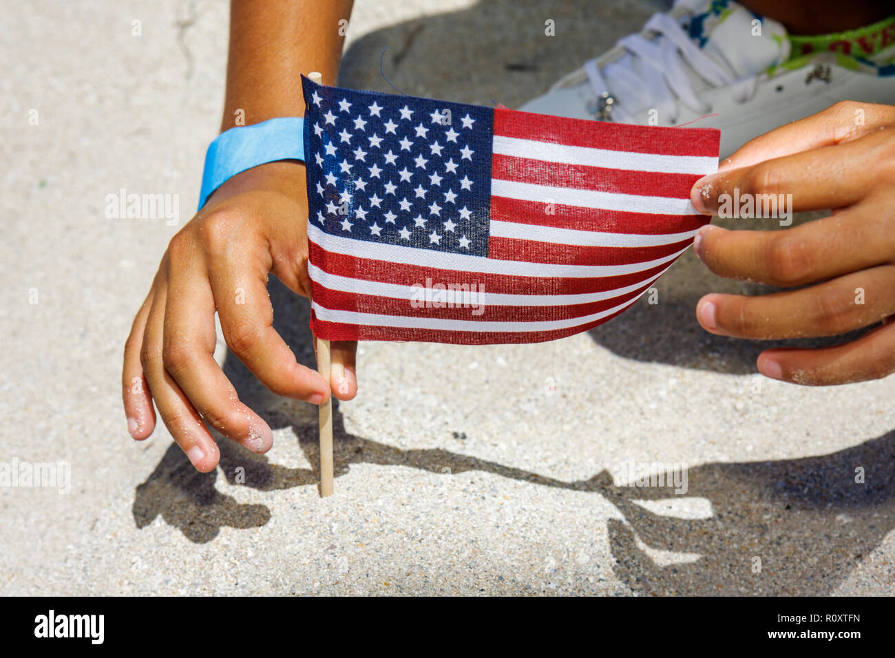 Miami Beach Florida,Flag Day,Stars & Stripes,child's,hand,hands,plant the flag,sand,FL090614065 Stock Photo
