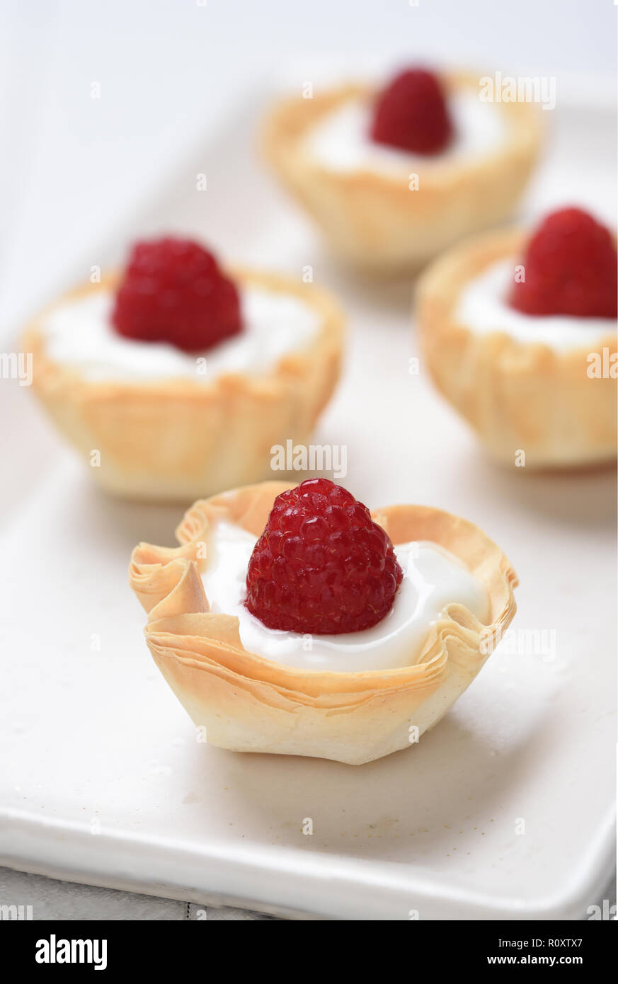 Closeup of Mini Fillo Shells filled with custard and topped with fresh raspberries. Stock Photo