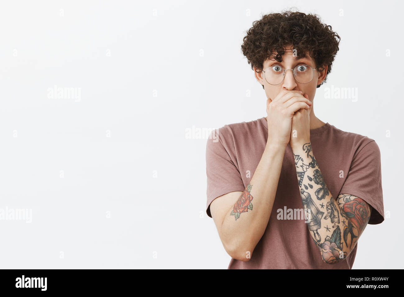 Man seeing friend making cool trick on skate gasping staring amazed and surprised covering mouth with hands popping eyes at camera standing impressed and shocked over gray background Stock Photo