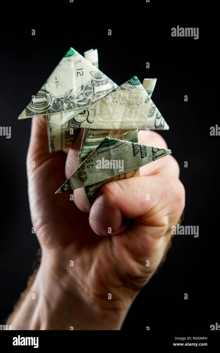 Hand Holds Origami Paper Money House For Real Estate And