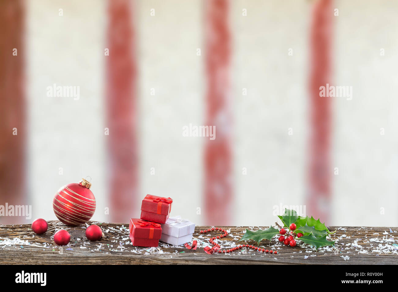 Christmas background with decorations Christmas' balls and gift boxes red on wooden board against timbered wall Stock Photo