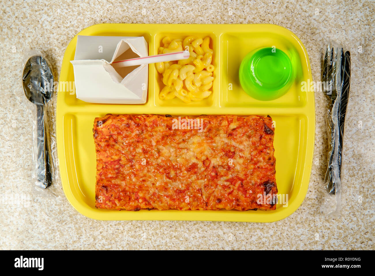 Grade school lunch tray with pizza with small carton of milk mac-n-cheese and green gelatin for dessert Stock Photo