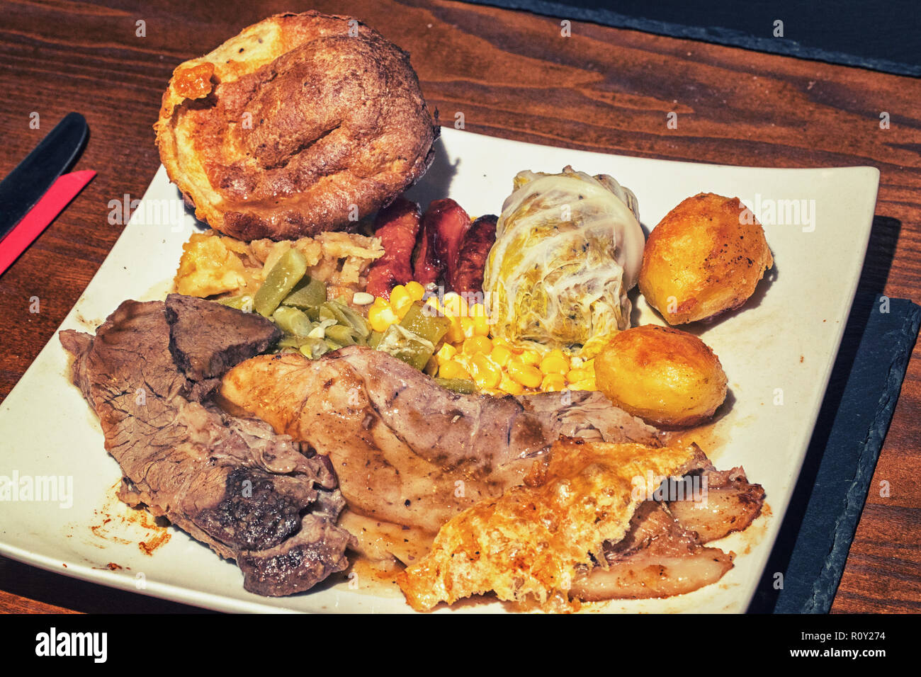 Sunday roast beef and pork dinner with roast potatoes, beans, sweetcorn
