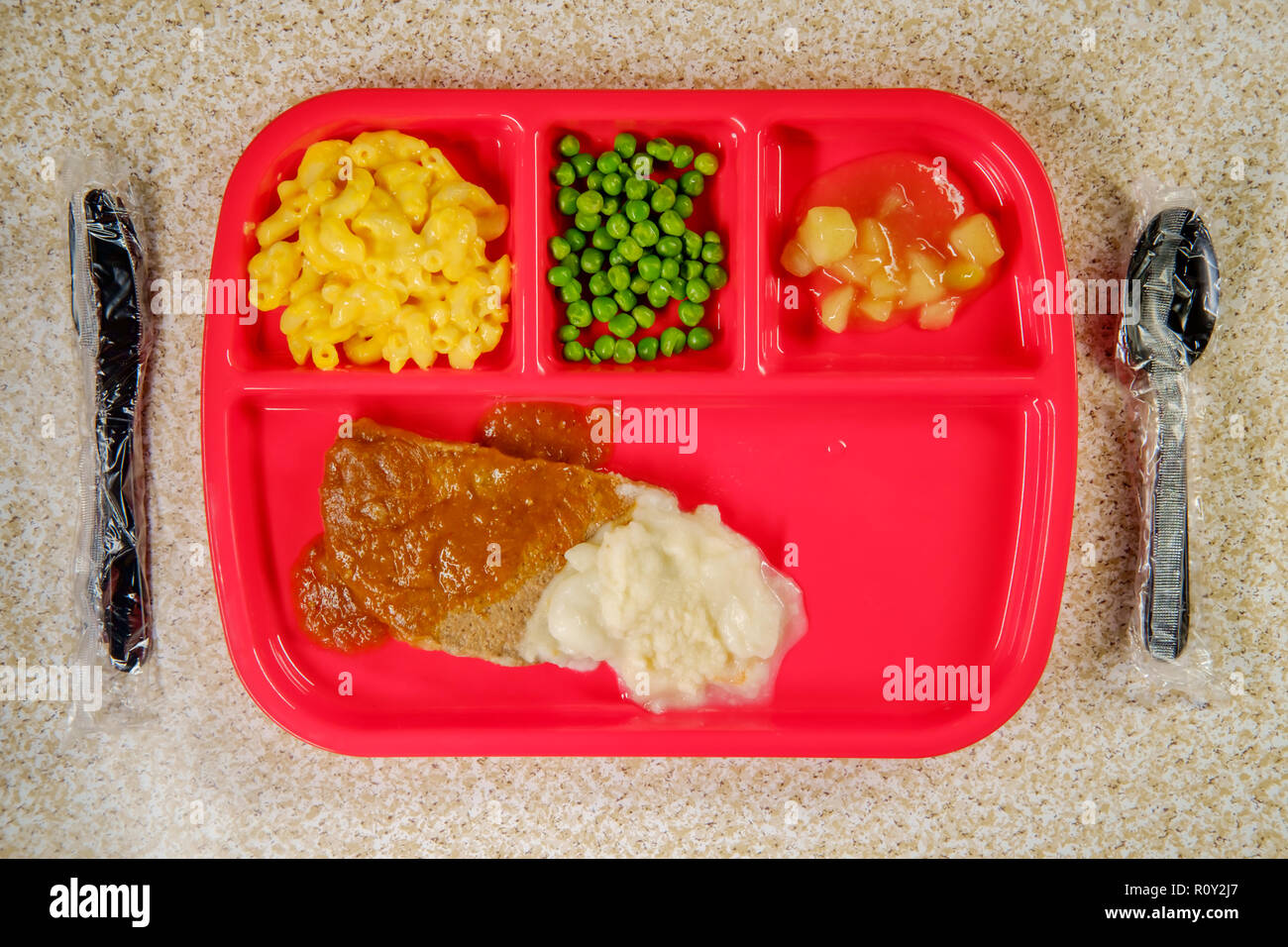 Grade school lunch salisbury steak on tray with peas macaroni and cheese and apple sauce Stock Photo