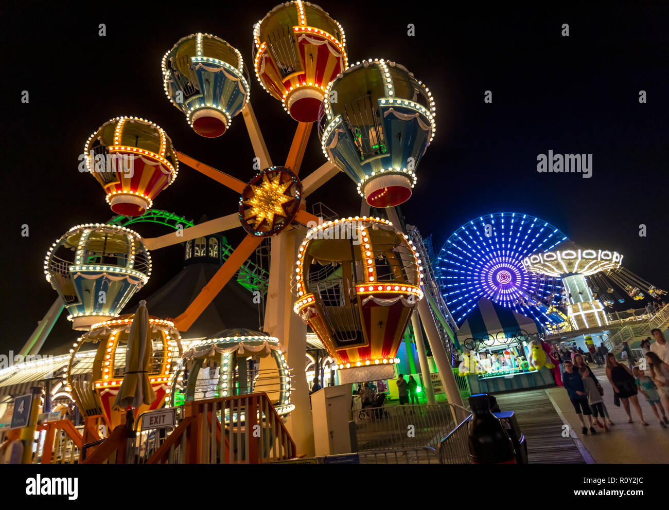 An amusement park with rides riders at nighttime at the ocean shore. Stock Photo
